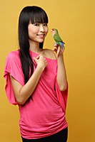 Young woman holding lovebird on her hand - Asia Images Group