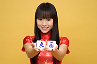 Young woman holding Chinese dice meaning "east & west" - Asia Images Group