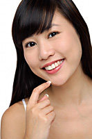 Young woman smiling, finger to chin, portrait - Asia Images Group