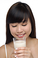 Young woman holding glass of milk, eyes closed - Asia Images Group
