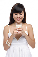 Young woman holding glass of milk, looking down at milk - Asia Images Group