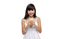 Young woman wearing white dress and holding glass of milk - Asia Images Group