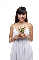 Young woman wearing white dress and holing small plant - Asia Images Group