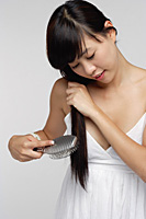 Young woman wearing white dress and brushing hair - Asia Images Group