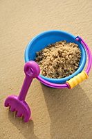Beach Bucket filled with sand and shovel leaning against bucket - Asia Images Group
