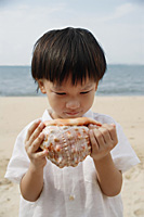 Young boy on beach looking at giant conk shell - Asia Images Group