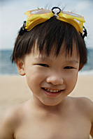 Young boy on beach with yellow swimming goggles on head, smiling, portrait - Asia Images Group