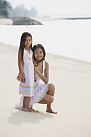 Mother and daughter on beach wearing white dresses, portrait - Asia Images Group