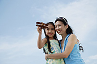 Mother and daughter flying wooden airplane, mother holding daughter - Asia Images Group