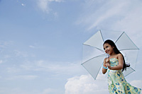 Young girl holding blue umbrella over head - Asia Images Group