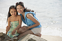 Mother and daughter on beach by rocks - Asia Images Group