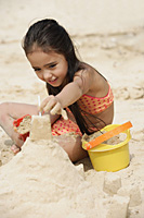 Young girl building sand castle on beach - Asia Images Group