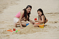 Mother and daughter on beach, building sand castle - Asia Images Group
