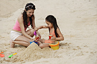 Mother and daughter building sand castle on beach - Asia Images Group