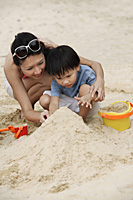 Mother and son building sand castle on beach - Asia Images Group
