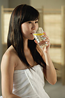 Young woman wrapped in towel drinking lemon water - Asia Images Group