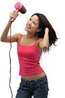 Young woman blow drying hair and smiling - Asia Images Group