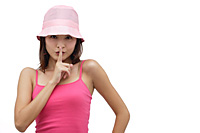 Young woman wearing pink hat with finger to mouth, be quiet please - Asia Images Group