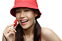 young woman wearing red hat and holding whistle, looking at camera, smiling - Asia Images Group
