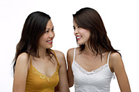 Two young women looking at each other, smiling - Asia Images Group