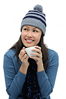 Young woman wearing winter hat and scarf and holding cup - Asia Images Group