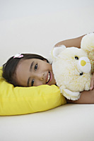 A young girl lying down with her teddy bear - Asia Images Group