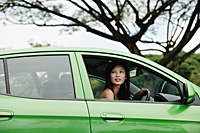 A young woman drives a green car - Asia Images Group