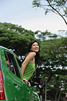 A young woman leans out of the window of a car - Asia Images Group