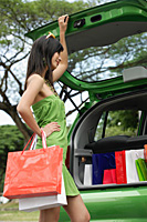 A young woman puts her shopping in the back of a car - Asia Images Group