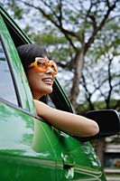 A young woman drives a green car - Asia Images Group