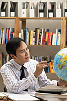 A man working with a globe on the desk - Asia Images Group