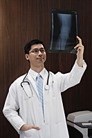 A doctor holds up an x-ray - Asia Images Group