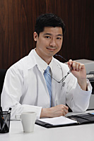 A doctor sits at his desk - Asia Images Group