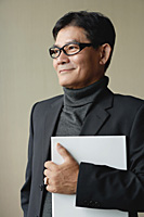 A man with glasses holding a white folder - Asia Images Group