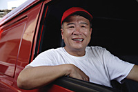 A man in a red van smiles at the camera - Asia Images Group