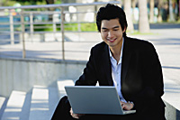 A man uses his laptop outdoors - Asia Images Group