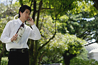 A man talks on his cellphone in the park - Asia Images Group
