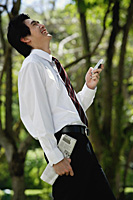 A man laughs as he checks his cellphone in the park - Asia Images Group