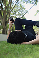 A man listens to music on a mp3 player in the park - Asia Images Group