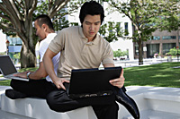 Two men use their laptops in the park - Asia Images Group