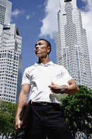 A man with a helmet stands in front of skyscrapers - Asia Images Group