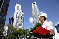 A man with a helmet stands in front of skyscrapers - Asia Images Group