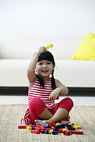 A small girl plays with blocks on the floor - Asia Images Group