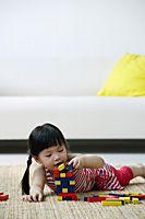 A small girl plays with blocks on the floor - Asia Images Group