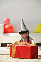 A young girl unwraps a birthday present - Asia Images Group