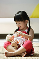 A small girl plays with a doll - Asia Images Group