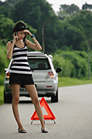 A woman with car trouble calls for help on her cellphone - Asia Images Group