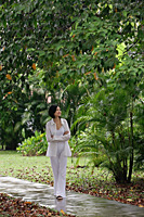 A woman strolls down a path in a garden - Asia Images Group