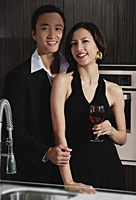 A couple smile at the camera while in the kitchen - Asia Images Group