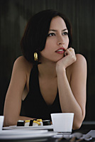 A woman sits at a table with a plate of sushi - Asia Images Group